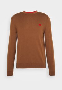 Pull marron à manches longues avec col rond, bordures côtelées aux poignets et à l'ourlet, arborant un petit patch logo rouge sur le côté gauche de la poitrine.