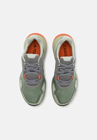 Lightweight athletic shoes in green with gray mesh upper. Features orange accents and grey laces. Textured sole for traction and grip.