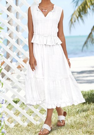 Weißes, ärmelloses Kleid mit geraffter Taille und Rüschensäume. Gewebte Textur, kombiniert mit hellen Slip-On-Sandalen mit dekorativen Details.