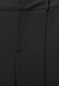 Čierne nohavice z hladkej tkaniny, s predným vreckom, prispôsobeným strihom a precíznym prešívaním pozdĺž švov.