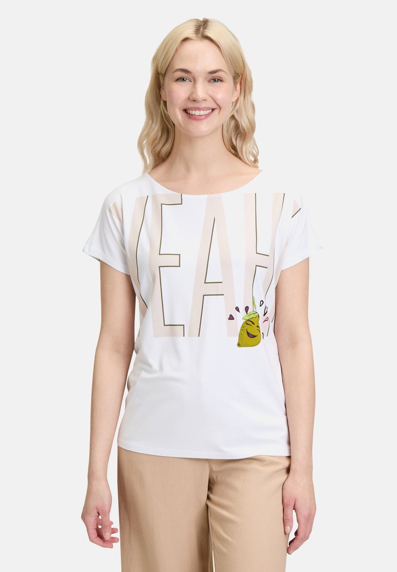 Witte t-shirt met korte mouwen waarop het woord "YEAH" in grote beige letters staat en een cartoon taco afbeelding met harten aan de linkerkant.