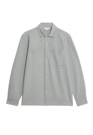 Chemise boutonnée gris clair à manches longues, fabriquée dans un tissu doux, dotée de deux poches à l'avant et d'un design de col traditionnel.