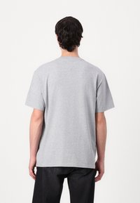 Szara bawełniana koszulka, krótki rękaw, okrągły dekolt, luźny krój, gładka faktura, z prostym dołem. Brak widocznych logo lub wzorów.