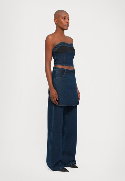 Mustasa denim strapless yläosa, jossa on kontrastivärinen musta vyö. Yhdistetty leveälahkeisiin tummansinisiin denimhousuihin ja vastaavaan denimmini-hameeseen.