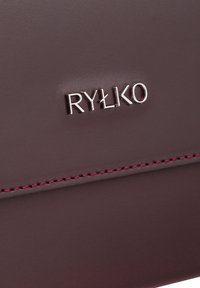 Burgunderrotes Lederportemonnaie mit silbernem RYLKO-Logo. Texturierte Oberfläche mit kontrastierendem pinkfarbenem Stich, der das Design akzentuiert.
