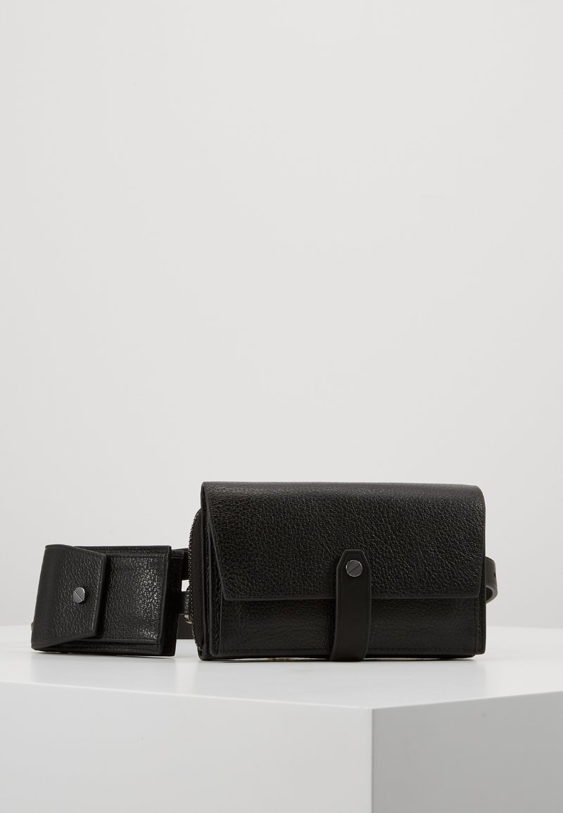 Svart texturerad läder crossbody-väska med viklock, magnetknäppning och avtagbar rem. Kompakt design för mångsidig användning.