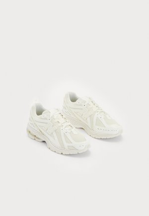 Weiße Sportschuhe aus Mesh- und synthetischen Materialien, Schnürdesign, gepolsterter Kragen und strukturiertes Profil für besseren Grip. Leichte Bauweise.