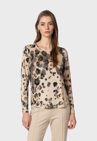 Dugi rukav bež majice s crnim i smeškim leopard uzorkom. Mekani materijal, okrugli izrez, ležeran kroj, suptilni bočni prorezi za dodatnu udobnost.