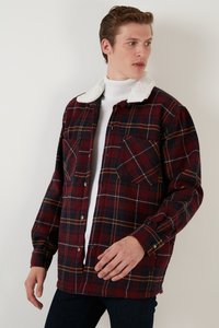 Cămașă flanelată în carouri roșie, bleumarin și galben, cu un guler din blană artificială albă, închidere cu butoni și două bucăți frontale. Mâneci lungi.
