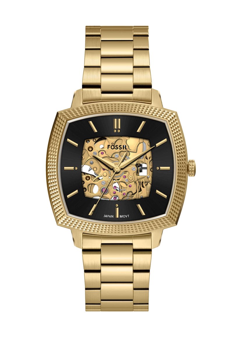 Montre Fossil carrée avec un bracelet en acier inoxydable doré, un cadran noir et des mécanismes exposés ornés d'accents dorés et roses.