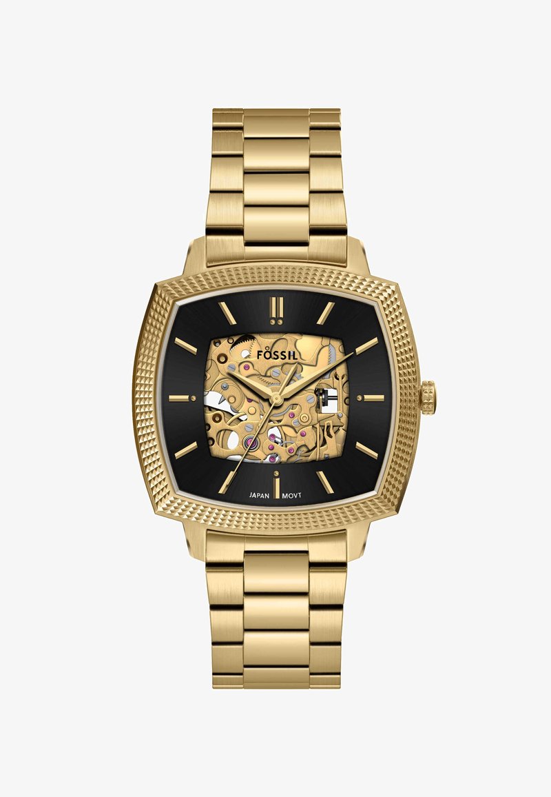 Montre Fossil carrée avec un bracelet en acier inoxydable doré, un cadran noir et des mécanismes exposés ornés d'accents dorés et roses.