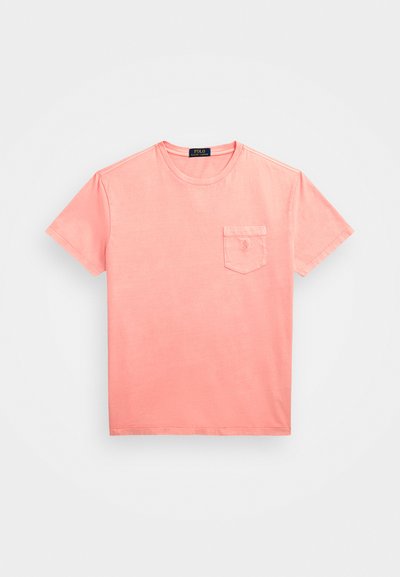 T-shirt de manga curta, cor-de-rosa coral, feita de algodão, com um bolso no lado esquerdo do peito e um pequeno logotipo. Gola redonda com detalhes de costura.