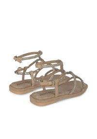 Sandali flat beige con più cinturini, adornati da dettagli metallici e una tomaia testurizzata. Soletta imbottita con suola leggera.