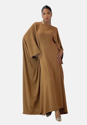 Brun asymmetrisk maxi kjole lavet af blødt stof med brede ærmer og draperingsdetaljer, parret med klare, udsmykkede hæle.