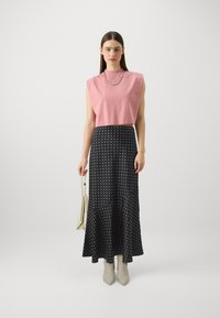 Rosa cropped topp og sort midi-skjørt med prikker. Glatt stoff, hulllengde, kombinert med lyse spisse ankelstøvletter og en liten håndveske.