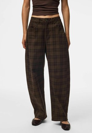 Personne portant un pantalon à carreaux marron foncé, taille haute, jambes larges, avec poches avant et ballerines marron foncé.