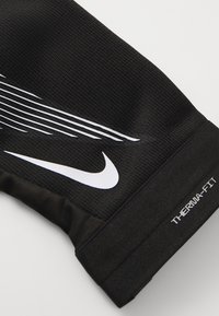 Black Therma-FIT sports sleeve with textured fabric, contrasting white Nike logo, and diagonal stripe pattern along the upper side.