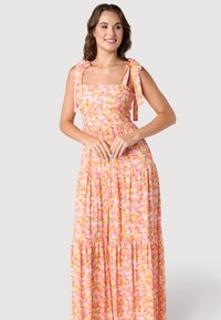 Robe maxi florale avec un décolleté carré, des bretelles à nouer et une jupe à volants dans des teintes de rose, orange et vert. Tissu léger avec une texture lisse.