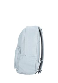 Sac à dos en tissu gris clair avec un design épuré, des bretelles rembourrées et une poche latérale. Présente une finition lisse et texturée.