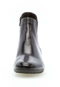 Bottine en cuir noir avec une texture lisse, bout rond et détail de fermeture éclair sur le côté. L'empeigne présente une douce accent en suède sur le dessus.