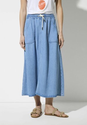 Light blue denim skirt with an elastic waistband, adjustable drawstring, and two front pockets. A-line shape, floor-length design.