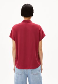 Korte mouwen, bordeauxrood shirt met een klassieke kraag, gladde stof en een iets losse pasvorm, gecombineerd met lichtblauwe denim shorts.