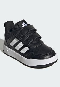 Crna sportska cipela sa gornjim dijelom od sintetičke kože, tri bijele pruge sa strane, velcro trake i bijeli srednji potplat.