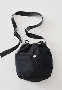 Borsa in nylon nera a forma arrotondata, con tracolla regolabile e una tasca frontale dotata di un fermaglio di colore argento.