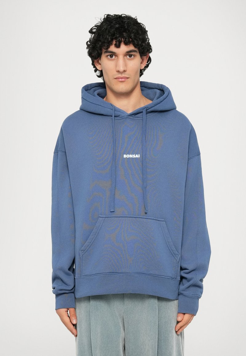 Haut à capuche bleu avec une poche avant, un cordon de serrage sur la capuche et le texte "BONSAI". Fait en tissu doux avec un motif subtil et une coupe décontractée.