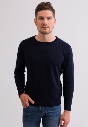Granatowy sweter z długimi rękawami i okrągłym dekoltem, wykonany z miękkiego materiału dzianinowego. Prosty wzór, lekka tekstura.