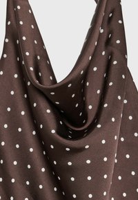 Brown silky fabric with white polka dots, draped smoothly to show texture and sheen.