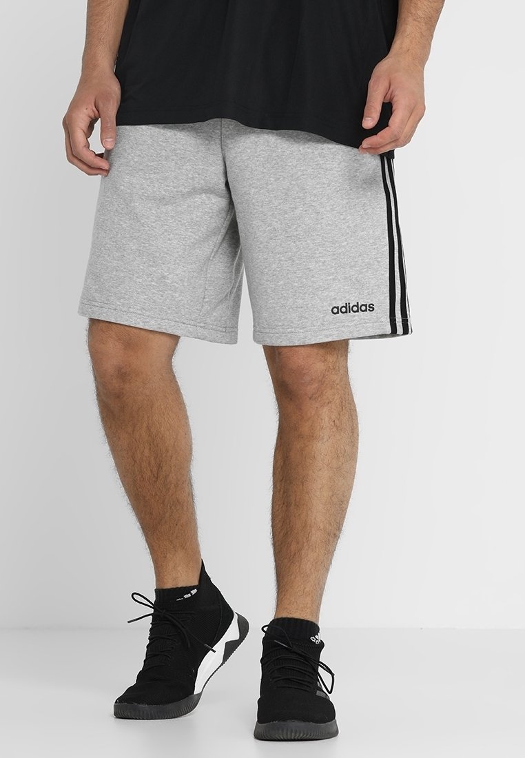 Grå träningsshorts i bomullsblandning med svarta sidostråkar och en broderad logotyp. Bärs med svarta sneakers och en svart tröja.