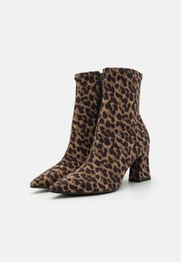 Bottines en imprimé léopard avec un bout pointu et un talon épais. Fabriquées en tissu avec une texture lisse. Fermeture éclair latérale pour un enfilage facile.