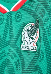 Grön Mexiko fotbollströja med emblem av en bevingad boll och detalj i röd, vit och grön krage.
