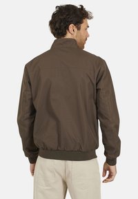 Veste bomber marron avec des poignets et un ceinture côtelés, présentant une texture lisse et un tissu respirant, vue de dos.