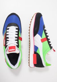 Chaussures de sport colorées présentant un mélange de matériaux bleus, verts, noirs et blancs. Suède texturé et tissu avec semelles en caoutchouc. Accents rouges.