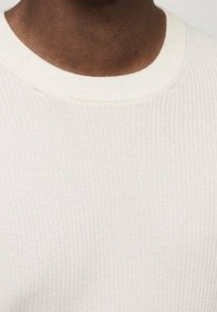 Pull en maille côtelée blanche avec un col rond et un tissu texturé, présentant une finition lisse et des détails de couture subtils.