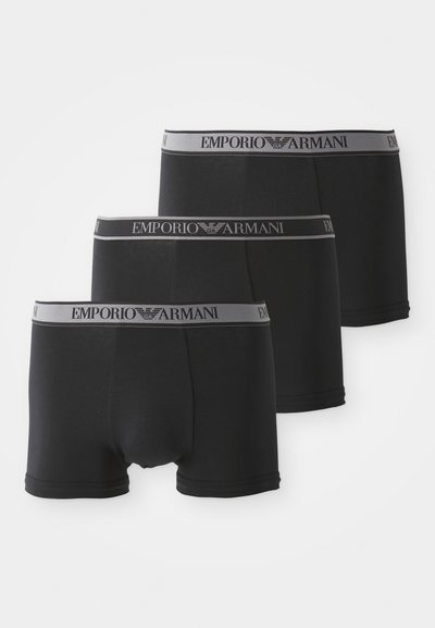 Trīs melnu bokseru apakšveļas komplekti ar mīkstu jostu, uz kuras ir uzraksts "Emporio Armani" pelēkā krāsā. Izgatavoti no gludas, elastīgas auduma.