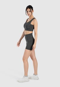 Donkergrijze sportoutfit bestaande uit een cropped sportbeha en hoge shorts, met een aansluitend ontwerp en contrasterende stiksels.