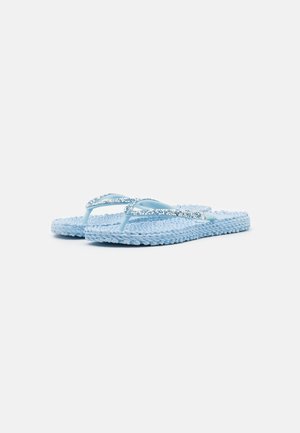 Lyseblå vævede flip-flops med glitrende remme, flad sål, vist side om side på en hvid baggrund.