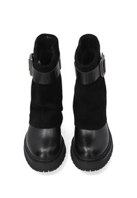 Schwarze Stiefeletten mit einer Kombination aus glattem Leder und weichem Wildleder. Das Design umfasst einen breiten Riemen mit einem silbernen Schnallenakzent.