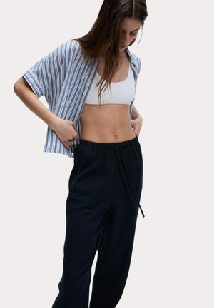 Chemise à manches courtes rayée bleu et blanc, ouverte à l'avant, associée à un pantalon noir à cordon de serrage. L'ensemble présente une coupe décontractée et confortable.