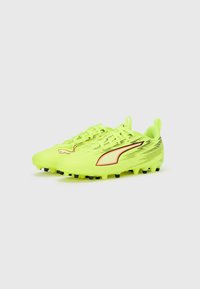 Botas de fútbol amarillo brillante con un diseño aerodinámico elegante, con tachones negros y líneas de acento rojas. Parte superior texturizada con sistema de cordones.
