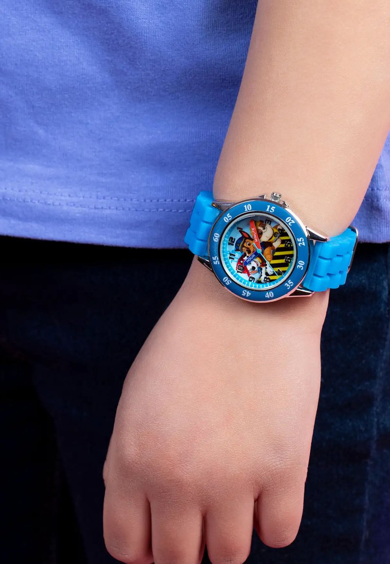 Montre-bracelet en silicone bleu avec un cadran rond, présentant un design de personnage coloré, des marqueurs d'heure et une lunette rotative.