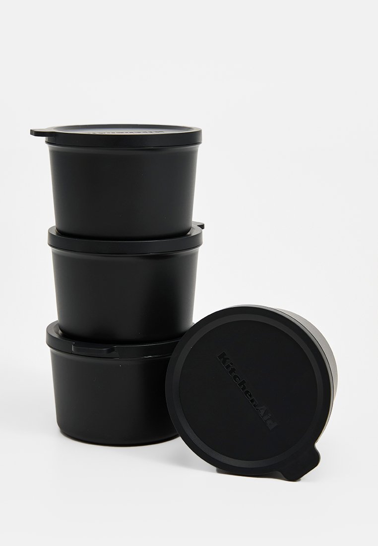 Zwarte plastic voedselopslagcontainers met bijpassende deksels, cilindrische vorm, stapelbaar ontwerp en gegraveerd "KitchenAid" logo op het deksel.