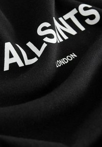 Schwarzes Baumwoll-T-Shirt mit weißem Aufdruck: "ALLSAINTS LONDON." Der Stoff wirkt weich, mit glatter Textur und leichter Dehnbarkeit.