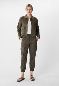 Olijfgroene cropped jas met vier voorzakken, lichtgewicht stof. Bijpassende tapping cargo pantalons met elastische boorden en een koord in de taille. Sandalen.