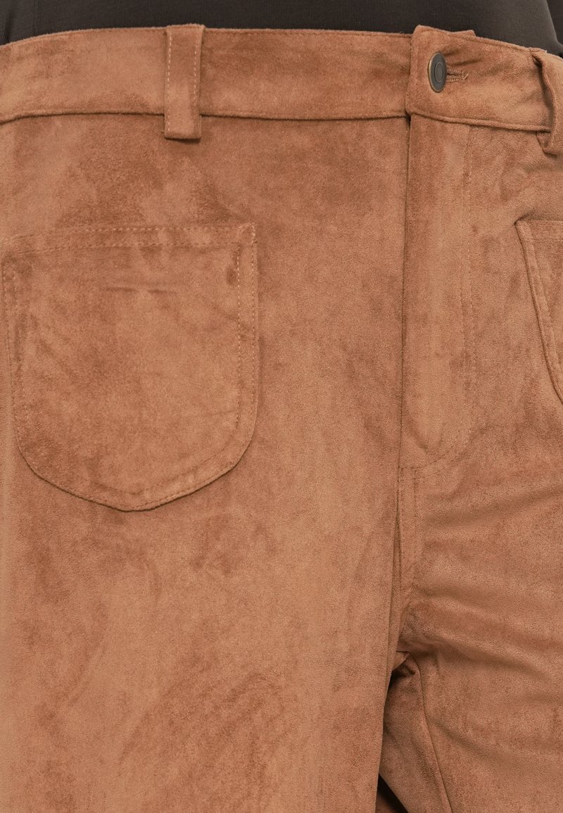 Brązowe zamszowe spodnie o miękkiej fakturze, z przodem zapinanym na guzik i widoczną tylną kieszenią. Tkanina ma delikatny połysk.
