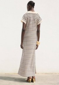Striped maxi dress in soft fabric, featuring a collared neckline and short sleeves. Colors include cream and navy stripes, with a fitted silhouette.