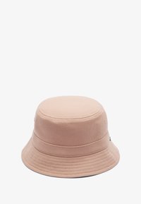 Sombrero tipo bucket de un suave color rosa, hecho de tela texturizada. Presenta una parte superior redondeada, un ala ancha y sutiles detalles de costura. Diseño ligero y casual.